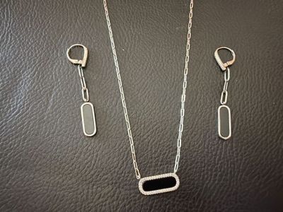 a silver necklace and earring set on a black leather surface