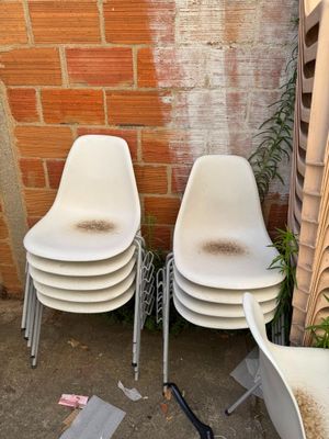 three white chairs sitting next to each other in front of a brick wall