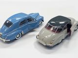 two toy cars sitting next to each other on a white surface