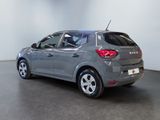 the back end of a grey car in a room with a white wall