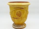 un vase jaune posé sur un socle, sur une surface blanche