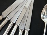 five knives and a spoon on a black table