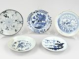 quatre assiettes bleues et blanches ornées de motifs sur fond blanc