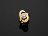 a gold ring with a diamond on a black surface