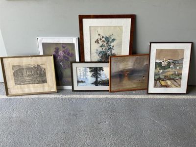 many framed pictures on the floor next to a wall