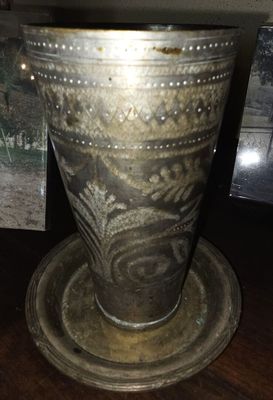 un vase en argent posé sur une table à côté d'un tableau représentant un cheval