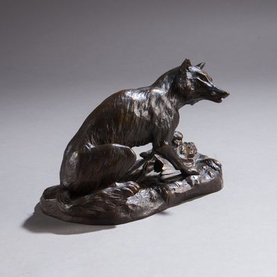 statue en bronze représentant un chien assis sur un rocher, un oiseau dans la gueule