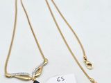 a gold necklace with a tag and a small black stone on it