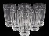 six verres transparents sont alignés en rangée sur une surface noire