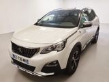 Une voiture blanche est garée dans une grande pièce au sol blanc.