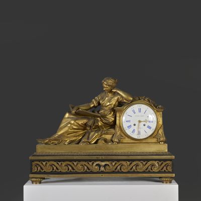 une horloge en or avec une femme assise dessus