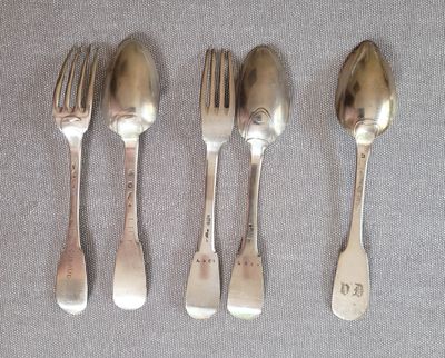 trois cuillères en argent et une fourchette sont alignées sur une table