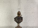 an antique oil lamp on a wooden table with a white wall in the background
