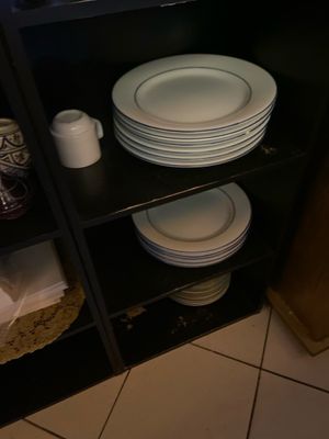 une étagère sur laquelle sont posées des assiettes et des tasses, dans une cuisine