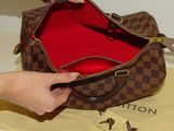 a woman opening a louis vuitton bag on a table