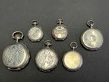 six antique silver pocket watches on a black surface