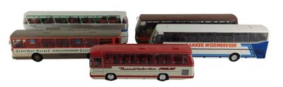 Quatre petits bus sont alignés en rang sur une surface blanche