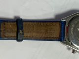 someone is holding a watch with a blue band on a white surface