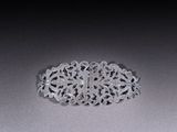 an antique silver broochle on a gray surface