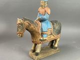 figurine représentant une femme à cheval, coiffée d'un chapeau bleu