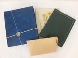 trois livres sont alignés sur un drap blanc orné d'une fleur