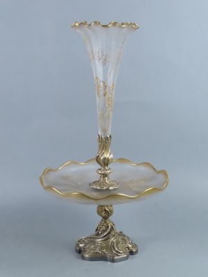 a gold plate with a glass vase on top of it