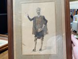 someone holding a picture of a man in a kilt on a table