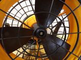 yellow and black fan sitting on top of a wooden floor next to a white wall