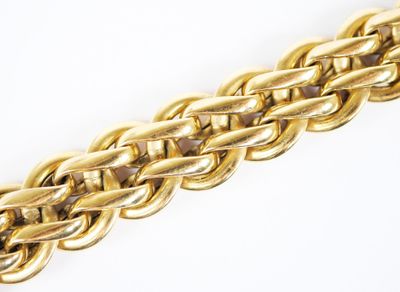 gros plan d'un bracelet en chaîne en or sur une surface blanche