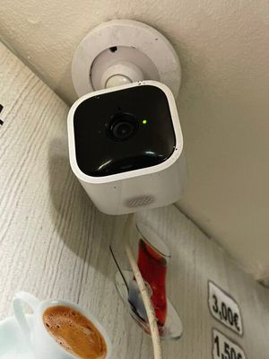 a small camera attached to the wall next to a cup of coffee