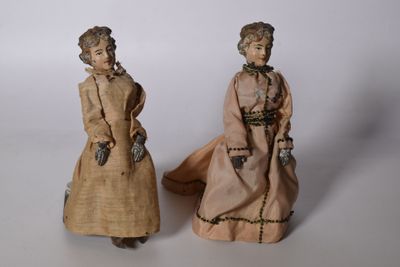 paire de poupées anciennes représentant des femmes en costume d'époque sur fond blanc