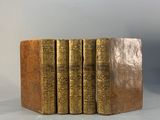 six vieux livres sont empilés sur une table