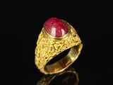 a close up of a gold ring with a red stone