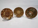 trois assiettes ornées de motifs, posées sur une surface blanche