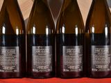 four bottles of wine are lined up on a red cloth