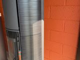 a tall metal object sitting on the floor next to a brick wall