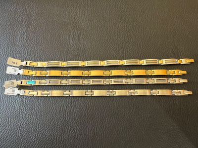 three pieces of gold colored metal bracelets on a black surface