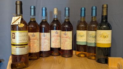 several bottles of wine are lined up on a wooden table