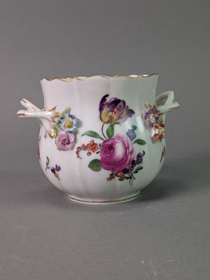 un vase blanc orné de fleurs, posé sur une surface grise