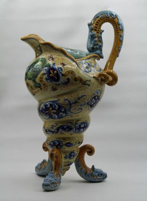 a blue and yellow vase with a handle on a stand