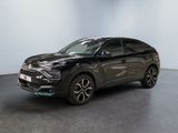 Une voiture noire est garée dans une pièce aux murs blancs.