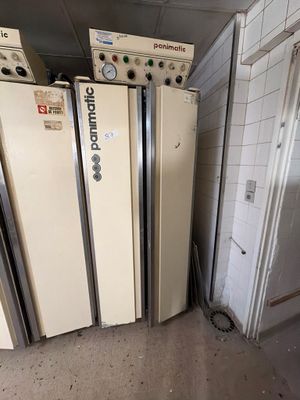 Plusieurs réfrigérateurs sont alignés contre un mur dans une pièce.