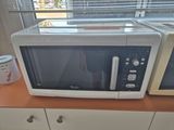 two microwaves sitting on a counter near a window