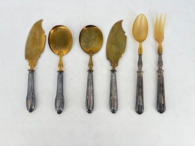 five silver and gold spoons and a knife on a white surface