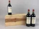 trois bouteilles de vin sont posées sur une caisse en bois