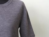 the back of a woman ' s grey sweater with a black collar