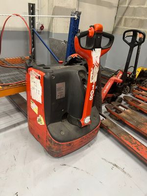 a red forklift in a warehouse with pallets on the floor