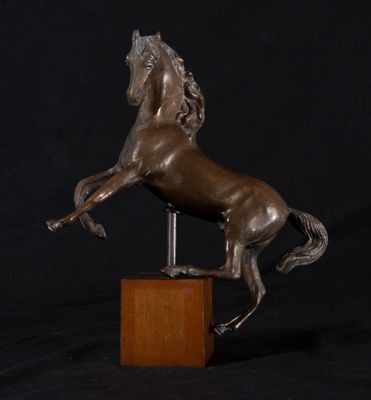 statue en bronze représentant un cheval dressé sur ses pattes arrière, posée sur un socle en bois
