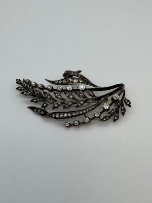 un gros plan d'une broche ornée d'une fleur et de feuilles