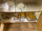 several trays of food are sitting on a shelf in a cabinet